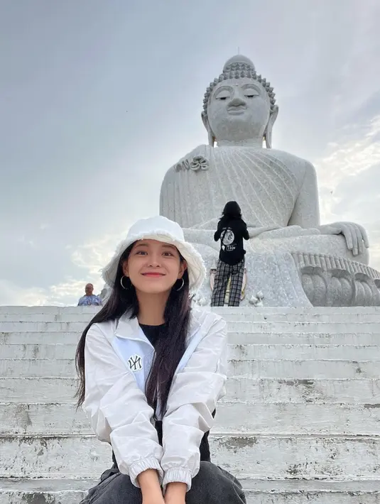 Kim Se Jeong saat berfoto di depan patung Budha yang besar, Ia tampak sangat flawless dengan topi putihnya. (Instagram/clean_0828)