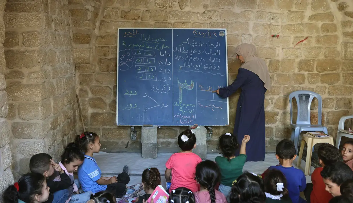 Anak-anak Palestina menghadiri kelas di sekolah bersejarah "Al-Kamaliya al-Othmanya" di Kota Tua Gaza yang menjadi bagian dari inisiatif sukarelawan yang diorganisir oleh para guru pengungsi, di Kota Gaza pada 2 November 2025. Di sisi lain, menurut data PBB, lebih dari 97 persen sekolah di Gaza mengalami kerusakan selama konflik. (Omar AL-QATTAA/AFP)
