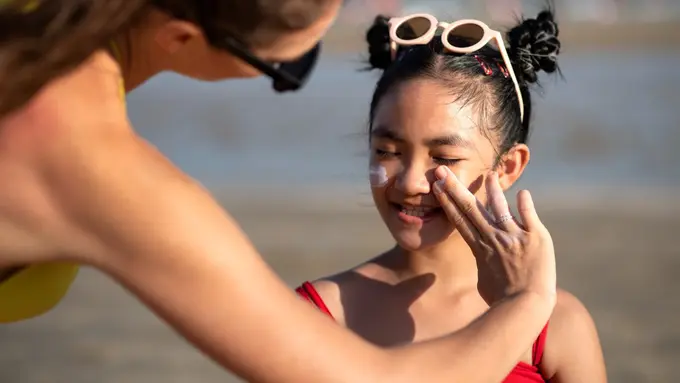 Seorang Ibu Sedang Mengoleskan Sunscreen Pada Anak