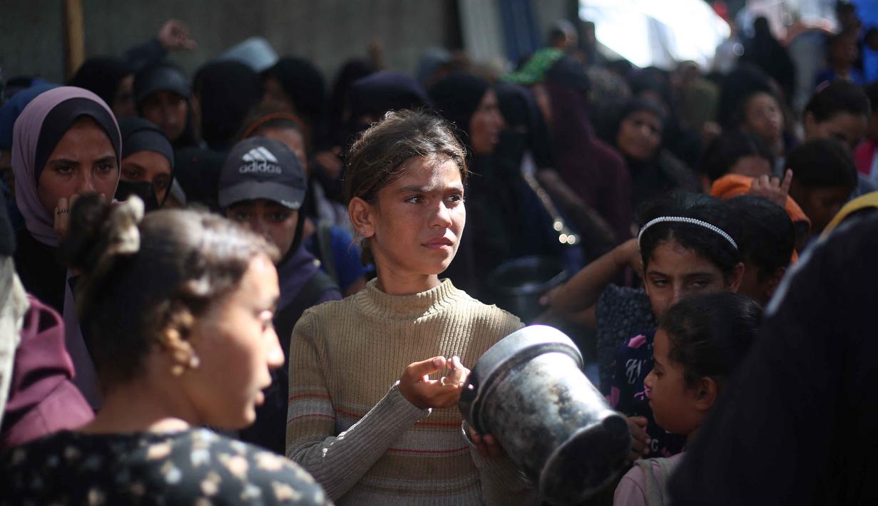 Anak-anak pengungsi Palestina berkumpul untuk menerima bagian makanan dari dapur amal di kamp pengungsi Nuseirat, yang terletak di bagian tengah Jalur Gaza, pada 21 Oktober 2025, atau sepekan setelah kesepakatan gencatan senjata antara Israel dan Hamas mulai berlaku. (Eyad BABA/AFP)
