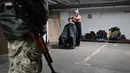 Seorang penata rambut memotong rambut seorang prajurit Pasukan Pertahanan Teritorial Ukraina, cadangan militer Angkatan Bersenjata Ukraina, di garasi bawah tanah yang telah diubah menjadi pangkalan pelatihan dan logistik di Kiev, pada Jumat (11/3/2022). (Sergei SUPINSKY / AFP)