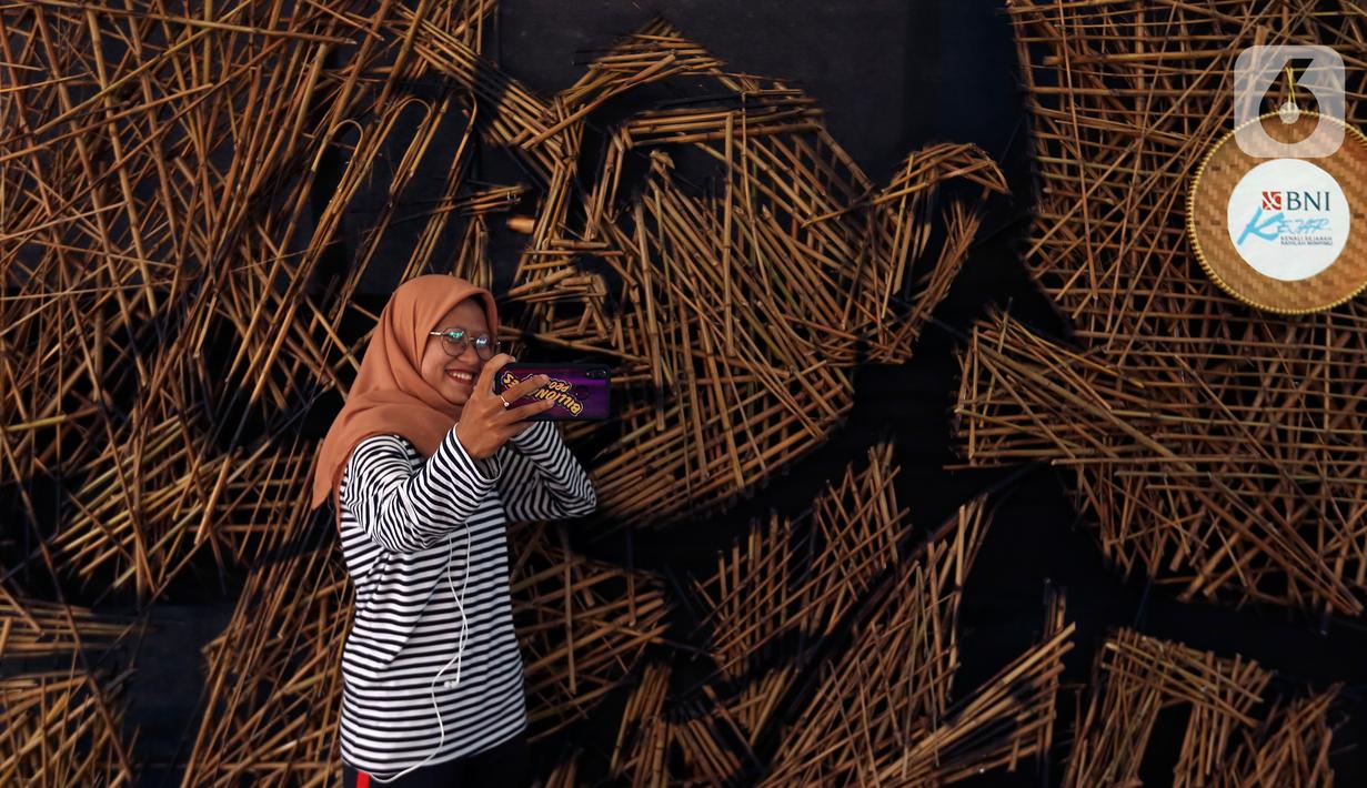 Pengunjung berswafoto di depan karya instalasi bambu berbentuk wajah Jenderal Sudirman karya Nus Salomo yang dipamerkan pada aksi Kenali Sejarah Raihlah Mimpimu di Terowongan Dukuh Atas, Jakarta, Minggu (24/11/2019). (Liputan6.com/Johan Tallo)