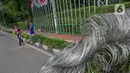 Pejalan kaki menghindari kawat berduri yang membentang menghalangi jalur pedestrian di Jalan Gatot Subroto, Jakarta, Selasa (2/2/2021). Keberadaan kawat berduri ini mengganggu akses pejalan kaki serta menutup jalur pemandu khusus penyandang disabilitas (guiding block). (Liputan6.com/Faizal Fanani)