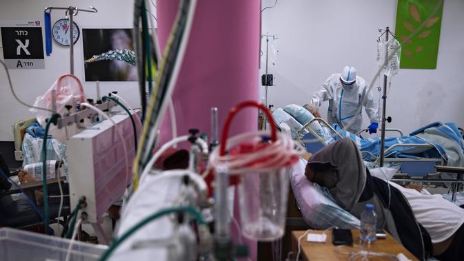 Petugas medis dengan alat pelindung diri merawat pasien COVID-19 di bangsal perawatan di Rumah Sakit Rambam di kota Haifa, Israel, Selasa (15/12/2020). Rumah sakit itu mengubah tempat parkir bawah tanah menjadi bangsal perawatan pasien terinfeksi corona sejak September lalu. (AP Photo/Oded Balilty)