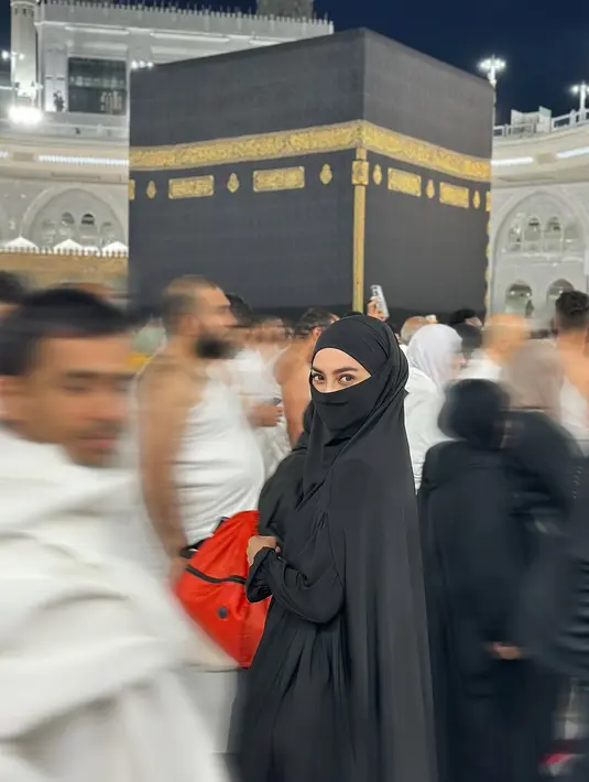 Berfoto di depan Khabah dan di tengah padatnya jamaah, Ririn Ekawati tampil misterius dengan khimar. Dipadu dengan  hijab dan cadar berwarna hitam [@ririnekawati]