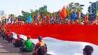 Buruh membentangkan bendera merah putih raksasa saat demo May Day di Surabaya. (Dian Kurniawan/Liputan6.com)