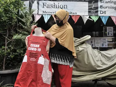 Siti Zahro (44) memajang celemek berbahan tas bansos Covid-19 buatannya di depan industri jahit rumahan KG-Lupe Fashion, Salemba, Jakarta, Senin (16/11/2020). Inovasi Siti bermula dari sepinya pesanan jahit akibat pandemi. (merdeka.com/Iqbal S. Nugroho)