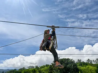 Seorang wanita dan bayinya menggunakan tali untuk menyeberangi sungai setelah banjir bandang yang menghancurkan desa-desa di sekitarnya di Ketol, provinsi Aceh, pada Selasa 6 Januari 2026. Lebih dari satu bulan setelah banjir bandang dan tanah longsor melanda sejumlah desa di Kecamatan Ketol, Aceh Tengah. (CHAIDEER MAHYUDDIN/AFP)
