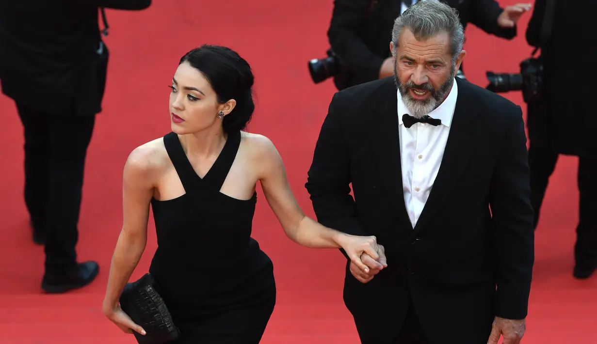 Aktor senior Mel Gibson tampak menggandeng mesra Rosalind Ross saat menaiki tangga karpet merah acara penutupan Festival Film Cannes ke-69 di Prancis, 22 Mei 2016. Pasangan beda usia 35 tahun ini tampak sedang dimabuk asmara. (François Xavier MARIT/AFP)