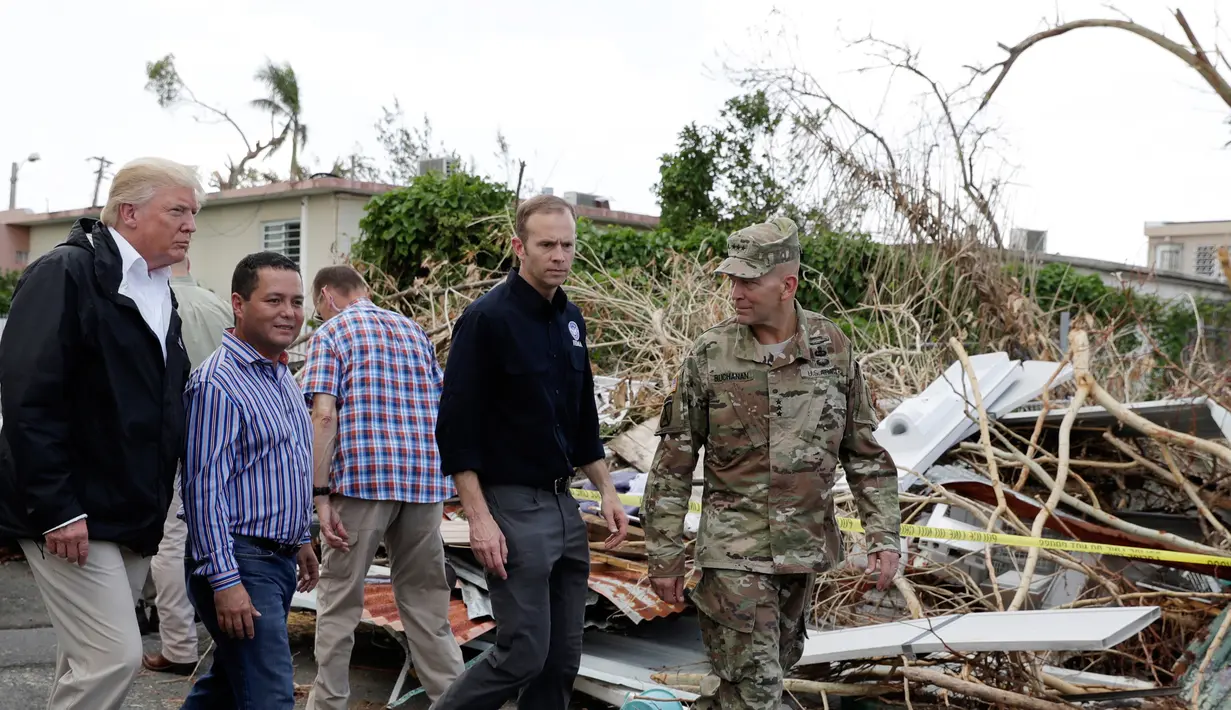 Presiden AS Donald Trump berkeliling ke permukiman warga yang rusak akibat terjangan Badai Maria di Guaynabo, Puerto Rico, Selasa (3/10). Trump menyaksikan langsung kehancuran akibat badai di Puerto Rico dan bertemu para pemimpin pulau itu (AP/Evan Vucci)