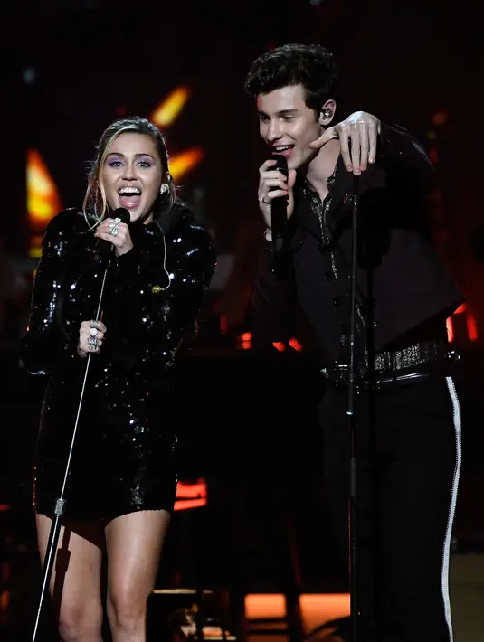 Miley Cyrus dan Shawn Mendes saat berduet di atas panggung MusiCares Person of The Year 2019 untuk menghormati Dolly Parton di Los Angeles Convention Center, California (8/2). (AFP Photo/Kevork Djansezian)