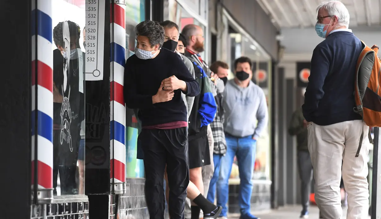 Para pria antre untuk memotong rambut di luar barber shop di Melbourne, Australia, Senin (19/10/2020). Warga Kota Melbourne, pada Senin (19/10), akhirnya bisa bernafas lega saat sejumlah pembatasan dilonggarkan setelah lockdown tahap keempat yang ketat selama sekitar 100 hari. (William WEST/AFP)