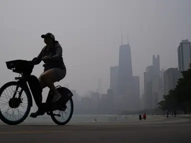 Seseorang mengendarai sepeda di sepanjang tepi Danau Michigan saat cakrawala pusat kota diselimuti kabut asap dari kebakaran hutan Kanada di Chicago, Selasa, 27 Juni 2023. (AP Photo/Kiichiro Sato)