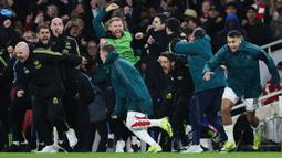Reaksi bahagia Mikel Arteta, tim pelatih, dan pemain cadangan Arsenal setelah menang atas Porto pada babak adu penalti saat laga leg kedua 16 besar Liga Champions 2023/2024 di Emirates Stadium, London, Inggris, Rabu (13/03/2024). (AFP/Adrian Dennis)