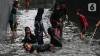 Anak-anak bermain air saat banjir merendam lingkungan rumah tempat tinggal mereka di kawasan kecamatan Kebayoran Baru, Jakarta, Senin (25/01/2021). Hujan deras yang mengguyur Jakarta hari ini, Senin (25/1) menyebabkan terjadinya banjir di kawasan permukiman tersebut. (Liputan6.com/Johan Tallo)