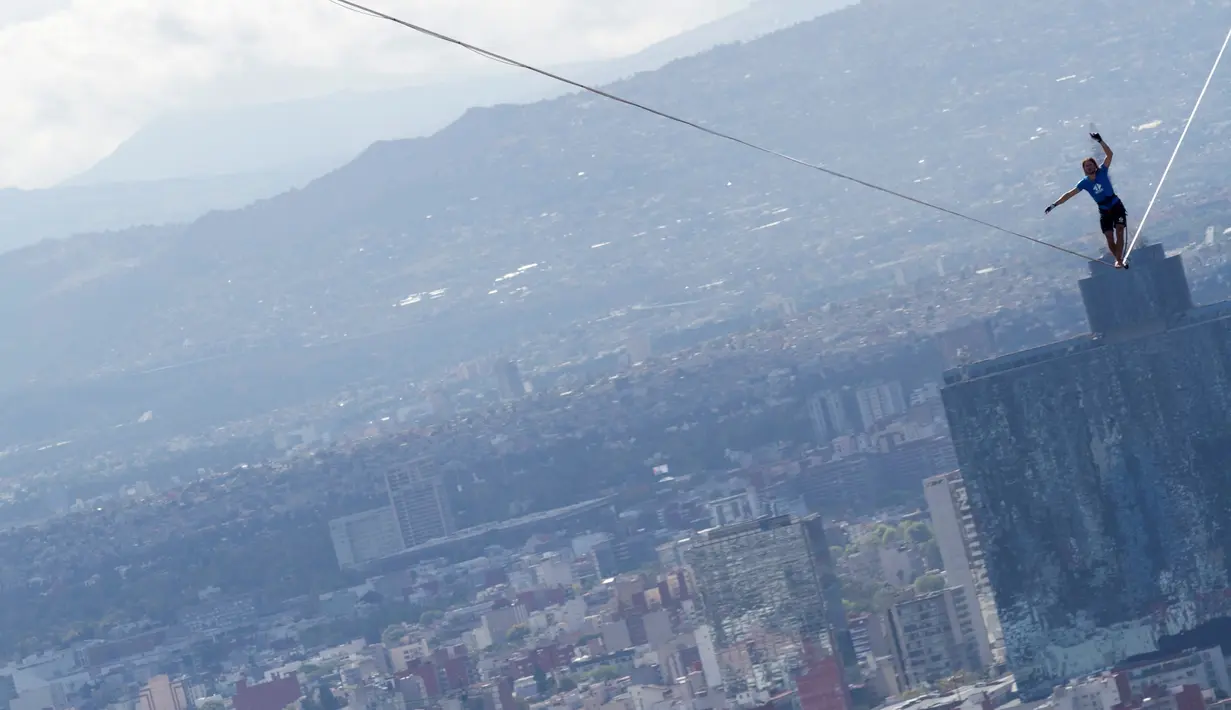 Alexander Schultz, asal Jerman mulai berjalan di antara dua gedung tertinggi Mexico City menggunakan tali pada ketinggian 246 meter di Meksiko, 4 Desember 2016. Schultz butuh lima kali usaha menaklukkan tali sepanjang 217 meter itu. (REUTERS/Stringer)