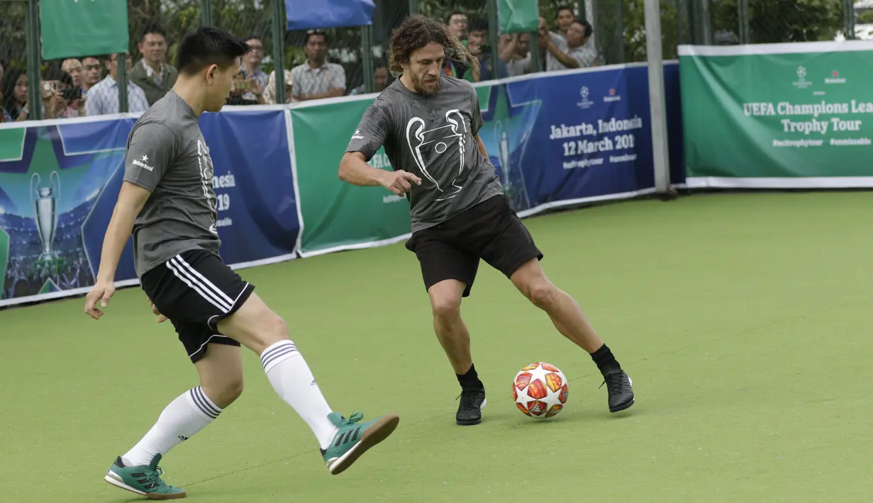 Legenda Barcelona, Carles Puyol, berusaha melewati pemain saat bermain futsal di Lapangan Menara Imperium, Jakarta, Selasa (12/3). Pertandingan tersebut merupakan bagian dari kegiatan UEFA Champions League Trophy Tour di Jakarta. (Bola.com/M Iqbal Ichsan)