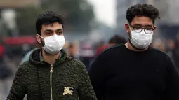 Dua pria mengenakan masker di sebuah jalan di Baghdad, Irak, (25/2/2020). Irak mengumumkan empat kasus baru COVID-19 di Provinsi Kirkuk, wilayah utara, pada Selasa (25/2), sehingga total pasien terinfeksi di negara itu bertambah menjadi lima orang. (Xinhua/Khalil Dawood)