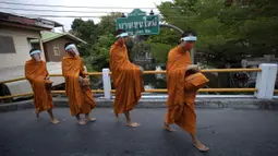 Para biksu Buddha memakai pelindung wajah untuk melindungi diri dari virus corona COVID-19 saat mengumpulkan sedekah di Bangkok, Thailand, Selasa (31/3/2020). Hingga 30 Maret 2020 sore, jumlah kasus COVID-19 di Thailand sebanyak 1.524 positif, 229 sembuh, dan 9 meninggal. (AP Photo/Sakchai Lalit)