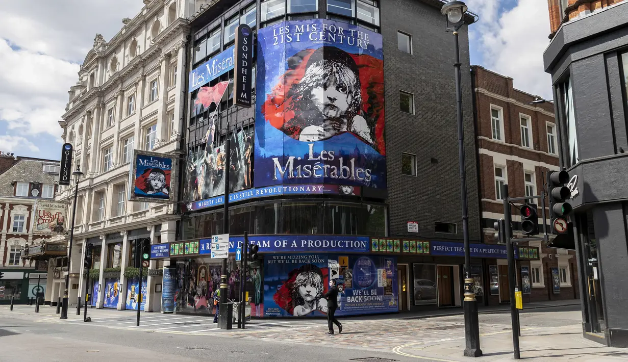 Seorang pria yang mengenakan masker berjalan melewati teater yang tutup di London, Inggris, 12 Mei 2020. Sedikitnya 5.000 pekerja teater di Inggris kehilangan pekerjaan selama diberlakukannya kebijakan penutupan (shutdown) akibat merebaknya COVID-19. (Xinhua/Han Yan)