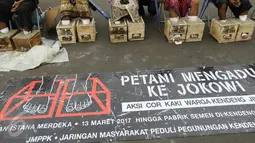 Sebuah spanduk besar yang didampang saat sejumlah Petani Kendeng, Pati menggelar aksinya di depan Istana Negara, Jakarta, Selasa (14 /3). (Liputan6.com/Helmi Afandi)