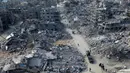 Foto udara memperlihatkan orang-orang berjalan melewati reruntuhan rumah di Rafah, Jalur Gaza Selatan pada 20 Januari 2025. (Foto oleh AFP)