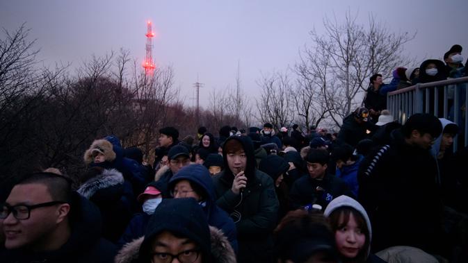 Orang-orang berkumpul di sudut pandang yang menghadap ke cakrawala kota untuk menyaksikan matahari terbit pertama tahun baru, meskipun dalam kondisi mendung, di Seoul, Korea Selatan (1/1/2020). (AFP/Ed Jones)