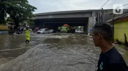 Petugas kepolisian mengatur lalu lintas saat banjir di Jalan Husein Nastranegara Perapatan Rawa Bokor, Tangerang, Sabtu (1/2/2020). Hujan deras yang mengguyur sejak Jumat (31/1) malam menyebabkan sejumlah kawasan di Tangerang terandam air. (merdeka.com/Imam Buhori)