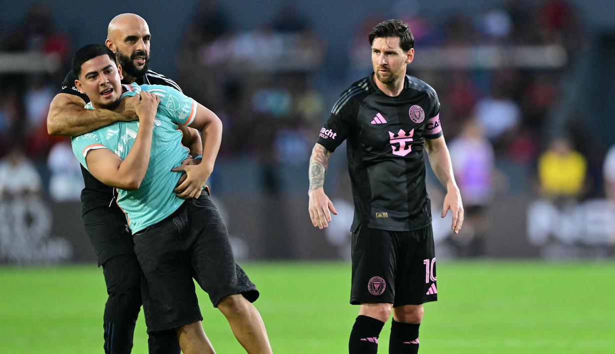 Pengawal Lionel Messi, Yassine Cheuko mengamankan seorang penyusup lapangan dalam laga persahabatan antara Inter Miami melawan Sporting San Miguelito di Stadion Romeo Fernandez, Panama, Amerika, Senin (03/02/2025) waktu setempat. (AFP/Martin Bernetti)