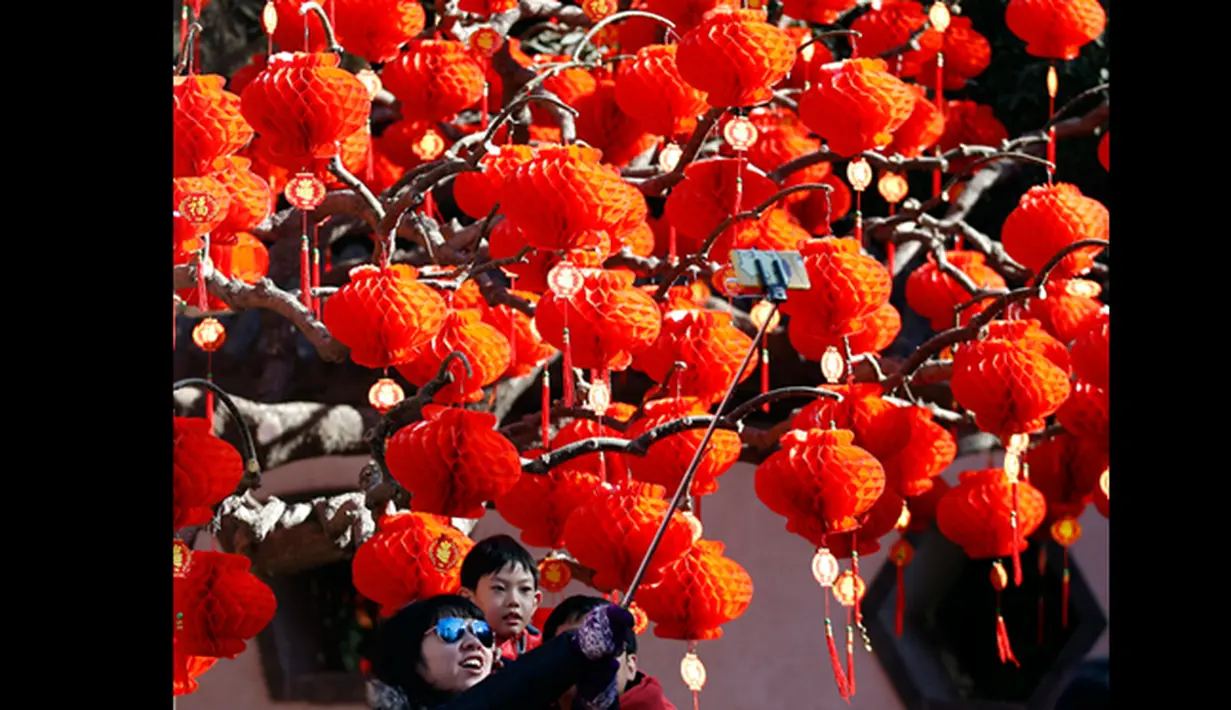 Salah satu keluarga saat berfoto di depan pohon yang dihiasi lampion dari perayaan Tahun Baru Cina di Ditan Park, Beijing (18/2/2015). Tahun Baru Imlek pada 19 Februari akan menyambut Tahun Domba. (Reuters /Kim Kyung-Hoon)