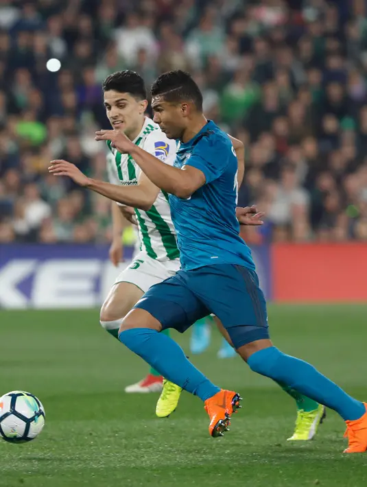 Pemain Real Madrid, Casemiro berebut bola dengan pemain Real Betis, Bartra pada laga pekan ke-24 La Liga Spanyol, di Estadio Benito Villamarin, Minggu (18/2). Real Madrid menang dengan skor 5-3. (AP/Miguel Morenatti)