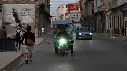 Kejadian ini memperparah krisis energi di Kuba yang disebabkan oleh infrastruktur yang sudah tua dan kekurangan bahan bakar akibat blokade minyak yang diperketat oleh Amerika Serikat. Tampak dalam foto, orang-orang beraktivitas di jalanan tanpa aliran listrik selama pemadaman listrik nasional di Havana, Kuba pada Sabtu 21 Maret 2026. (Yamil LAGE/AFP)