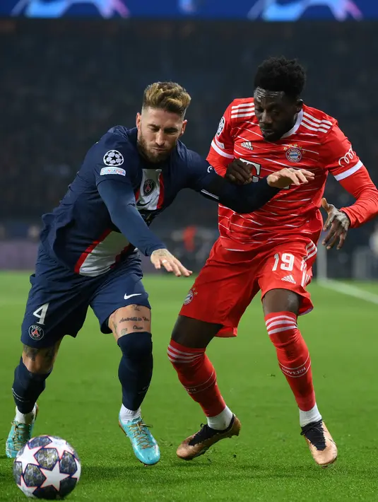 Bek PSG, Sergio Ramos (Kiri) berebut bola dengan gelandang Bayern Muenchen, Alphonso Davies selama pertandingan leg pertama babak 16 besar Liga Champions di stadion Parc des Princes di Paris, Rabu (15/2/2023). Bayern menang tipis atas PSG dengan skor 1-0. (AFP/Franck Fife)