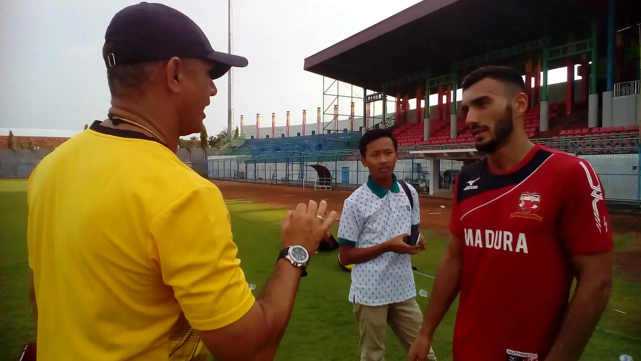 Gelandang Madura United, Redouane Zizu (kanan), berbincang dengan pelatih Gomes de Oliviera. Zizu tak bisa menghadapi Mitra Kukar karena cedera hamstring.