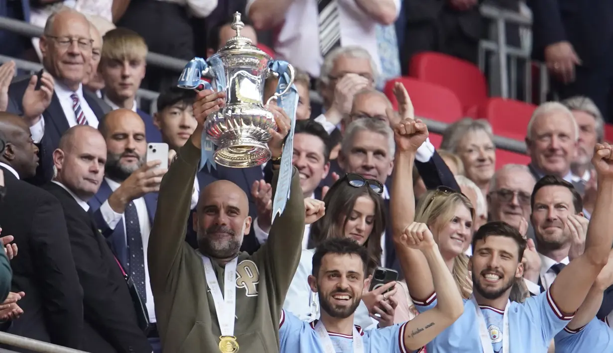 Pep Guardiola mengangkat saat mengangkat trofi Piala FA 2022/2023. (AP Photo/Dave Thompson)