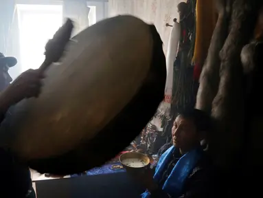 Seorang dukun menabuh alat musik saat mengusir roh jahat di kediaman pelanggannya di Kota Kyzyl, Tuva, Siberia, Rusia, (3 /11). Dukun-dukun kaum nomaden tersebut diyakini juga dapat menyembuhkan penyakit dan meramal masa depan. (REUTERS/Ilya Naymushin)