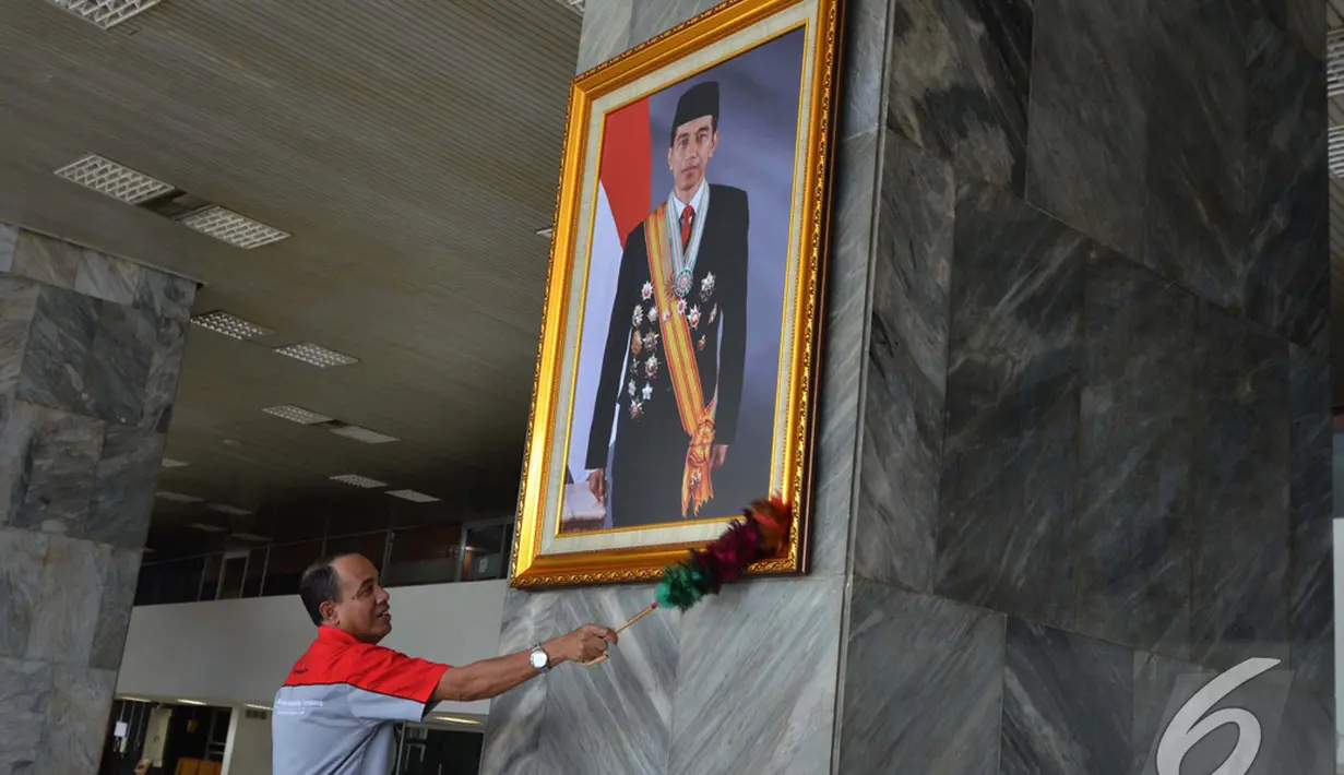 Petugas membersihkan foto presiden Joko widodo yang baru dipasang di pilar Gedung Nusantara III Kompleks Parlemen Senayan, Selasa (23/12/2014). (Liputan6.com/Andrian M Tunay)