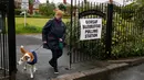 Seorang wanita bersama anjingnya meninggalkan sebuah tempat pemungutan suara pemilu parlemen Inggris di Cardiff, Wales, Kamis (8/6). Para pemilih mengajak anjingnya untuk menemani mereka mengambil bagian dalam Pemilu Inggris. (GEOFF CADDICK/AFP)