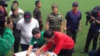 Presiden Joko Widodo membubuhkan tanda tangan di Buku Kurikulum Sepak Bola Indonesia dan Jaket Timnas Indonesia di depan Sekjen PSSI, Ratu Tisha Destria, saat peresmian Lapangan Timnas Indonesia di Senayan, Sabtu (2/12/2017). (Bola.com/Benediktus Gerendo)