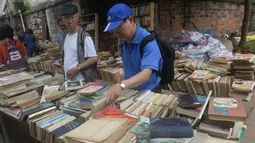 Warga mencari buku yang di jual selama pameran buku bekas di Hanoi, Vietnam  (26/10).( AFP Photo/Hoang Dinh Nam)
