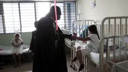 Seorang cosplayer berpakaian Darth Vader berbincang dengan seorang pasien saat acara amal oleh El Salvador Star Wars fan club di Rumah Sakit Benjamin Bloom Anak Nasional di San Salvador, El Salvador (14/12). (REUTERS/Jose Cabezas)
