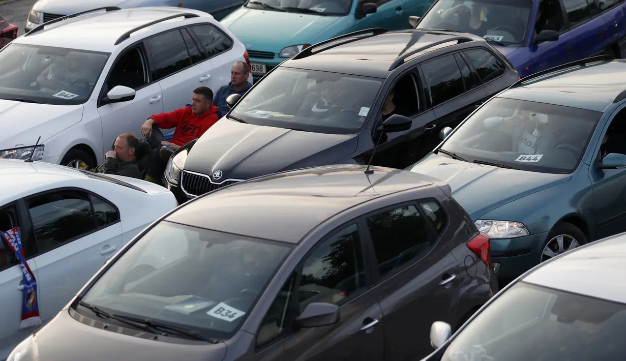 Suporter menyaksikan pertandingan Viktoria Plzen dan Sparta Praha di sebuah bioskop drive-in di Pilsen, Republik Ceko, Rabu (27/5/2020). Di tengah pandemi COVID-19, suporter Ceko dapat menyaksikan pertandingan bola lewat layar di bioskop drive-in. (AP Photo/Petr David Josek)