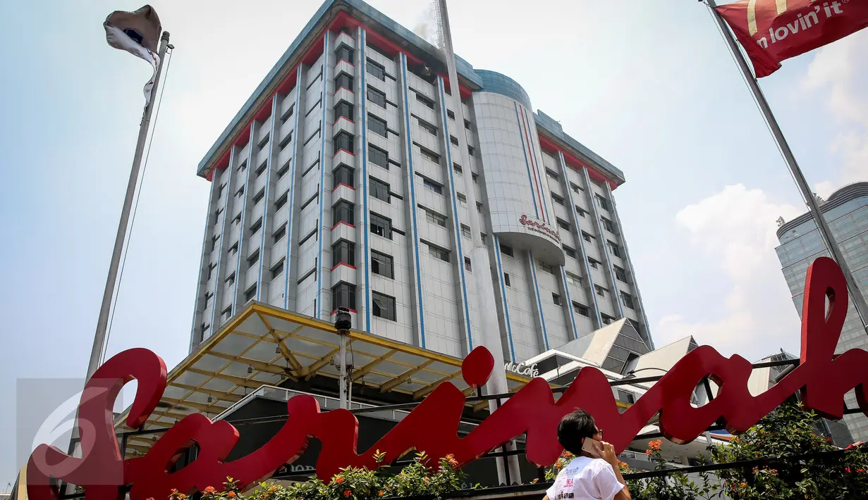 Warga berjalan di depan Gedung Sarinah yang tengah dilalap api, Jakarta, Kamis (15/10/2015). Lantai 14 gedung itu menjadi sasaran si jago merah. (Liputan6.com/Faizal Fanani)