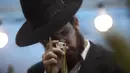 Seorang pria Yahudi memeriksa cabang-cabang palem, salah satu dari empat item yang digunakan sebagai simbol pada Hari Raya Sukkot, untuk menentukan apakah dapat diterima secara ritual sebelum membelinya di Yerusalem, 19 September 2021. (AP Photo/Sebastian Scheiner)