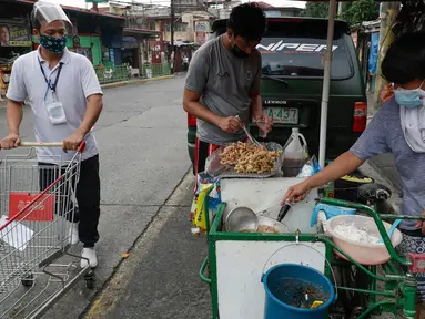 Seorang pria yang mengenakan masker membeli makanan dari warung kaki lima di kota Quezon, Filipina, Selasa (22/9/2020). Presiden Filipina Rodrigo Duterte mengatakan telah memperpanjang status masa darurat virus corona (Covid-19) di negaranya hingga satu tahun ke depan. (AP Photo/Aaron Favila)