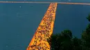 Ribuan orang berjalan di atas sebuah instalasi "The Floating Piers" yang merupakan karya seniman Bulgaria, Christo Vladimirov Javacheff di Danau Iseo, Italia, (24/6). Karya menakjubkan ini diharapkan dapat menarik wisatawan. (REUTERS/Stefano Rellandini)