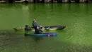 Orang-orang bermain kayak di sepanjang Sungai Chicago yang berwarna hijau jelang Hari Santo Patrick di Chicago, Amerika Serikat, Sabtu (13/3/2021). Setiap tahunnya, pewarnaan Sungai Chicago selalu menarik wisatawan. (Pat Nabong/Chicago Sun-Times via AP)