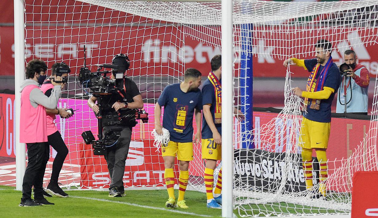 Bek Barcelona, Gerard Pique, melakukan selebrasi dengan menggunting jaring gawang usai menjuarai Copa del Rey di Stadion Olimpico de Sevilla, Minggu (18/4/2021). Barcelona menang 4-0 atas Athletic Bilbao. (AFP/Cristina Quicler)