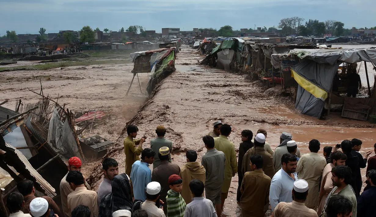 Warga terlihat pasrah melihat bangunan rumahnya hanyut tersapu banjir bandang di kawasan pasar di Peshawar, Pakistan, Minggu (3/4). Bencana yang menerjang wilayah Peshawar telah menghancurkan 852 rumah warga. (AFP/A Majeed)