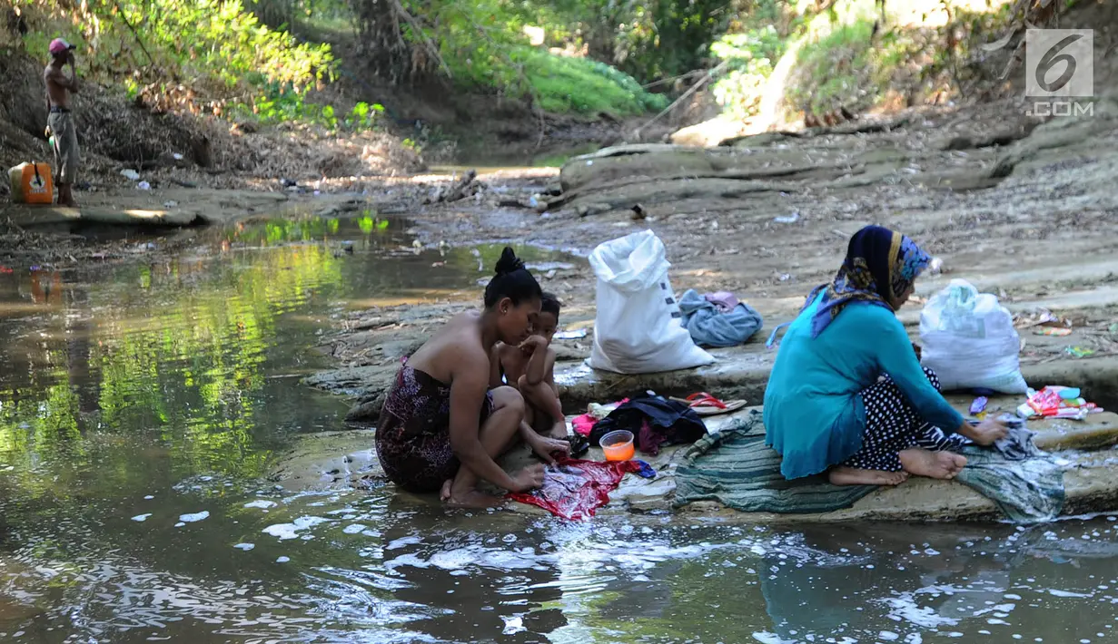 Warga mencuci pakaian dengan air dari lubang pada aliran Sungai Cihoe yang digunakan untuk memenuhi kebutuhan sehari-hari di Ridogalih, Cibarusah, Bekasi, Minggu (7/7/2019). Sudah lebih dari dua bulan, warga memanfaatkan sisa aliran sungai yang kotor akibat musim kemarau. (merdeka.com/Arie Basuki)